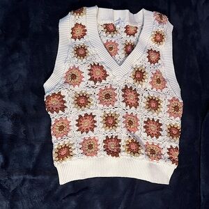 White v-neck sweater vest with sun patterns.